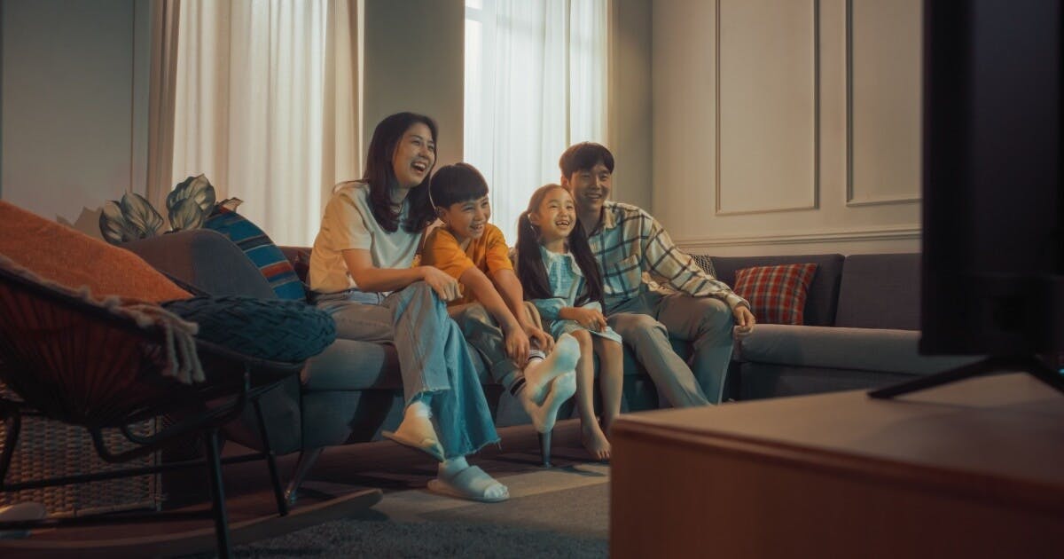 Uma família assistindo filme na sala. Pai, mãe, filho e filha.