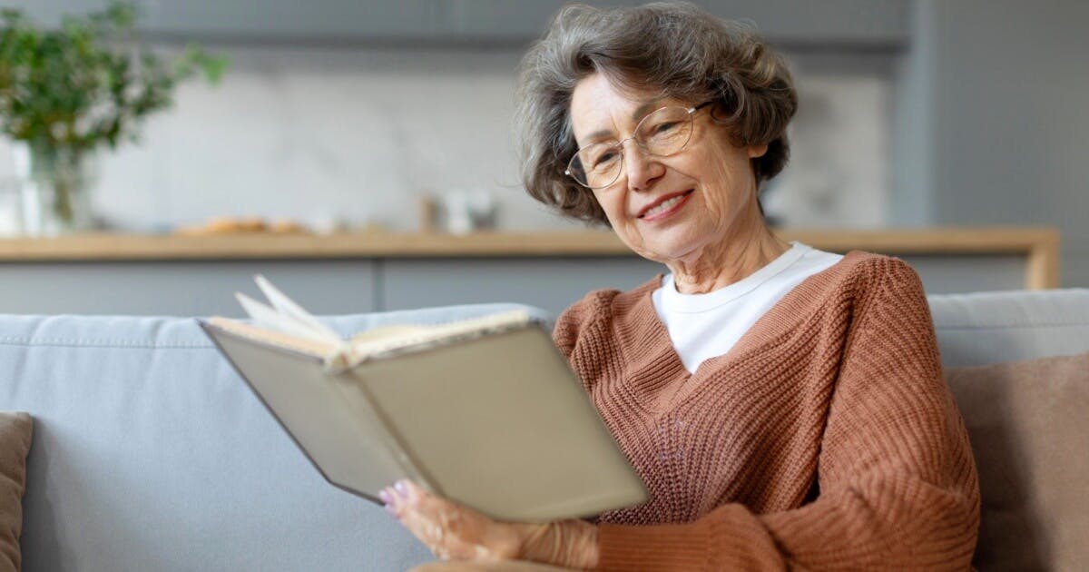 Mulher de óculos lendo um livro.