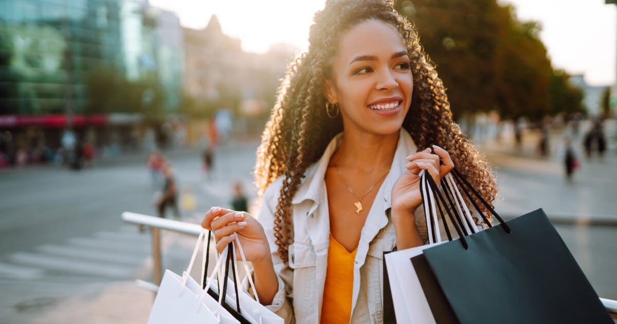 Uma mulher segurando sacolas de compras enquanto caminha pela cidade.