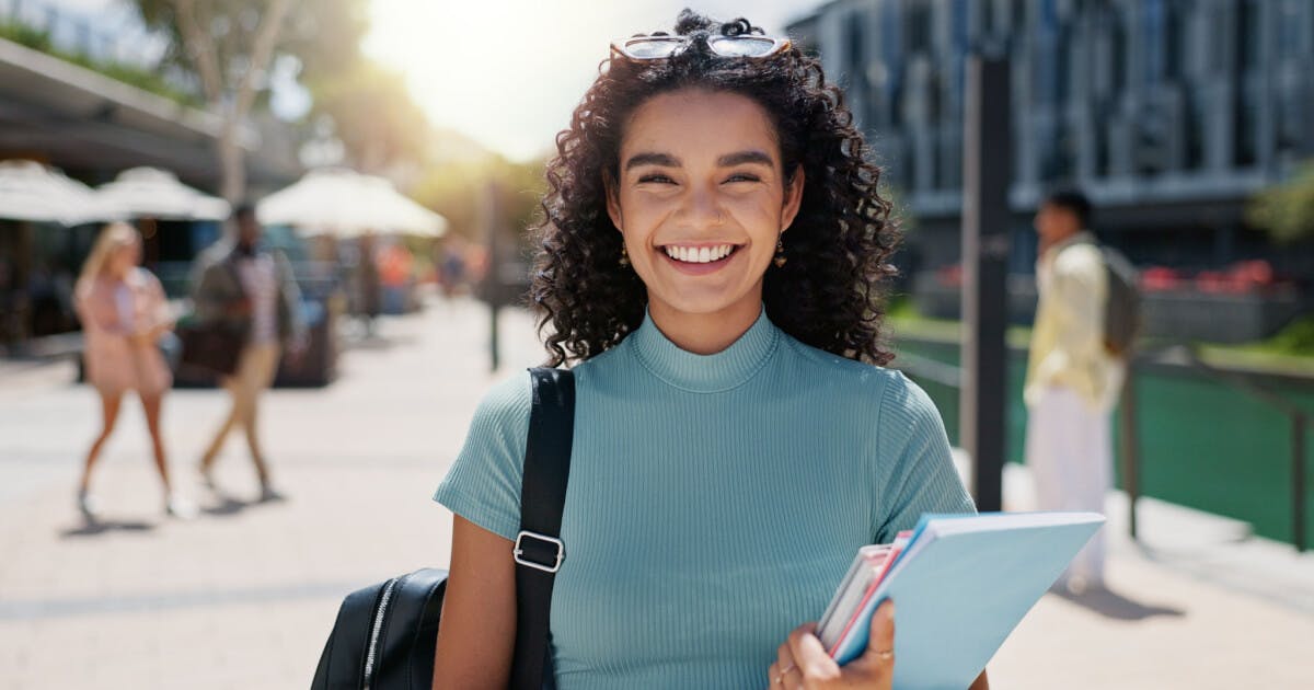 Uma jovem sorridente segurando um livro, expressando alegria e entusiasmo.