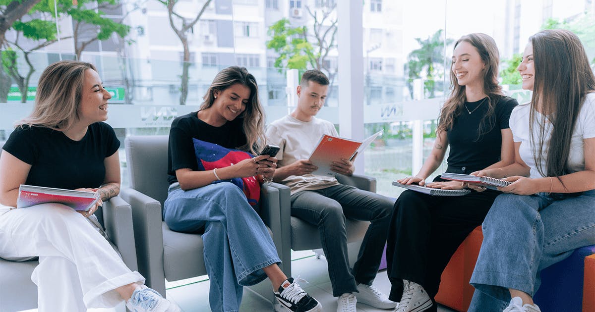 Quatro jovens sentados em cadeiras na KNN Idiomas, conversando e colaborando em um ambiente de aprendizado.
