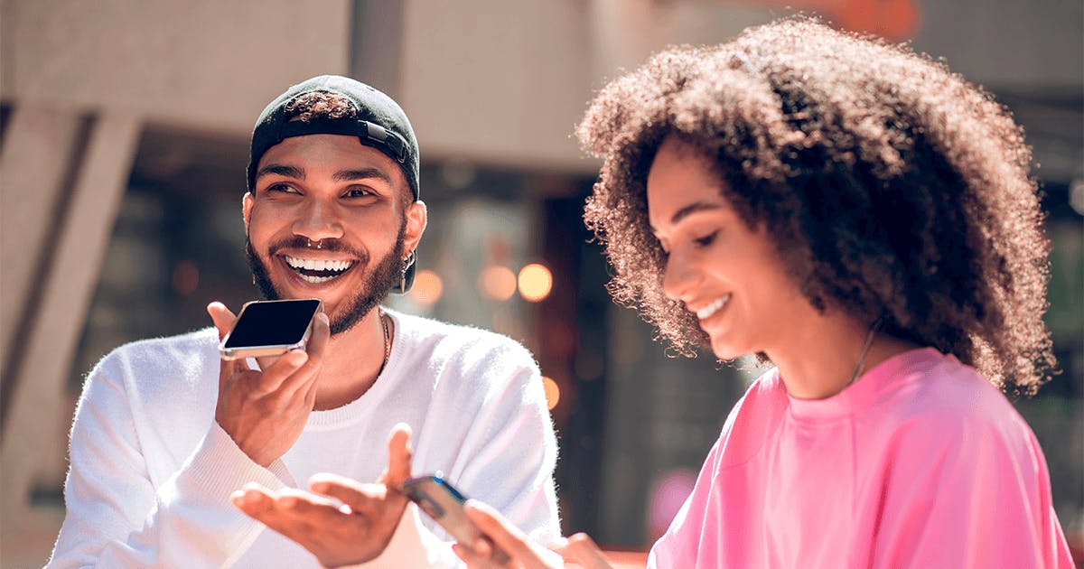 Um homem e uma mulher sorriem enquanto olham para seus celulares.
