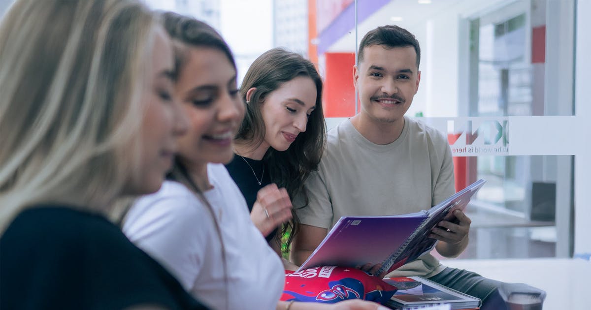Grupo de alunos KNN sorrindo e estudando juntos com material da escola