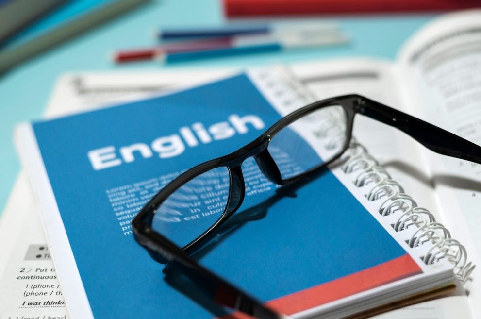 caderno de inglês com um óculos em cima