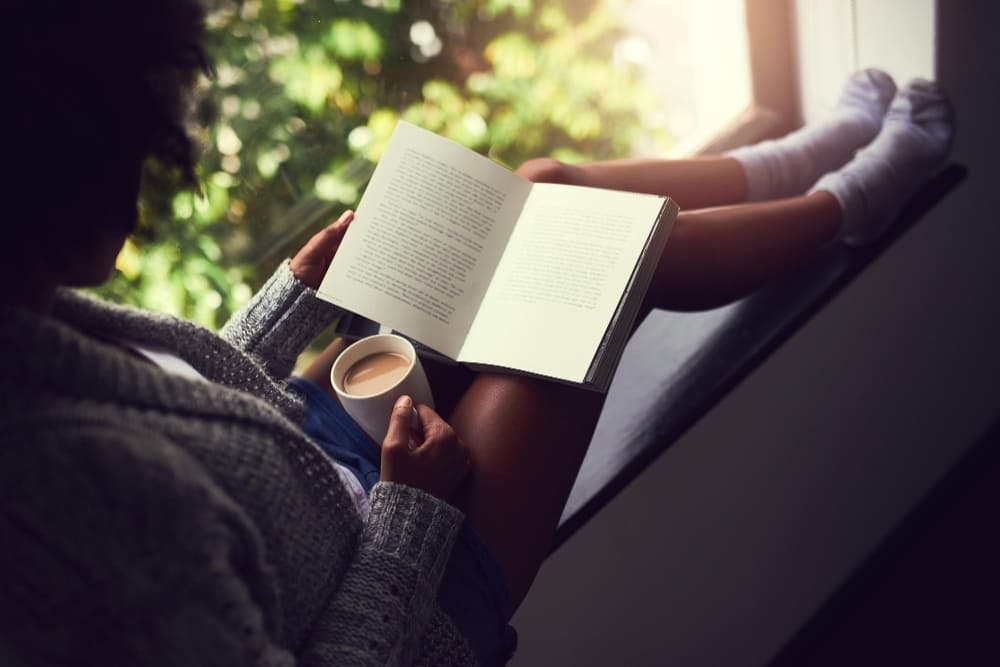Mulher lendo com um café na mão