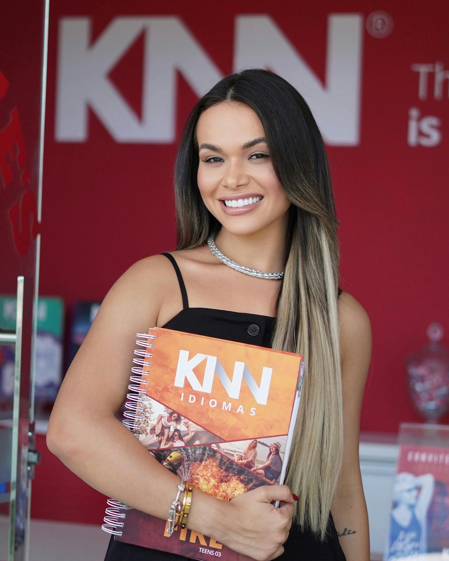 Foto de uma mulher com o livro da KNN Idiomas em mãos.