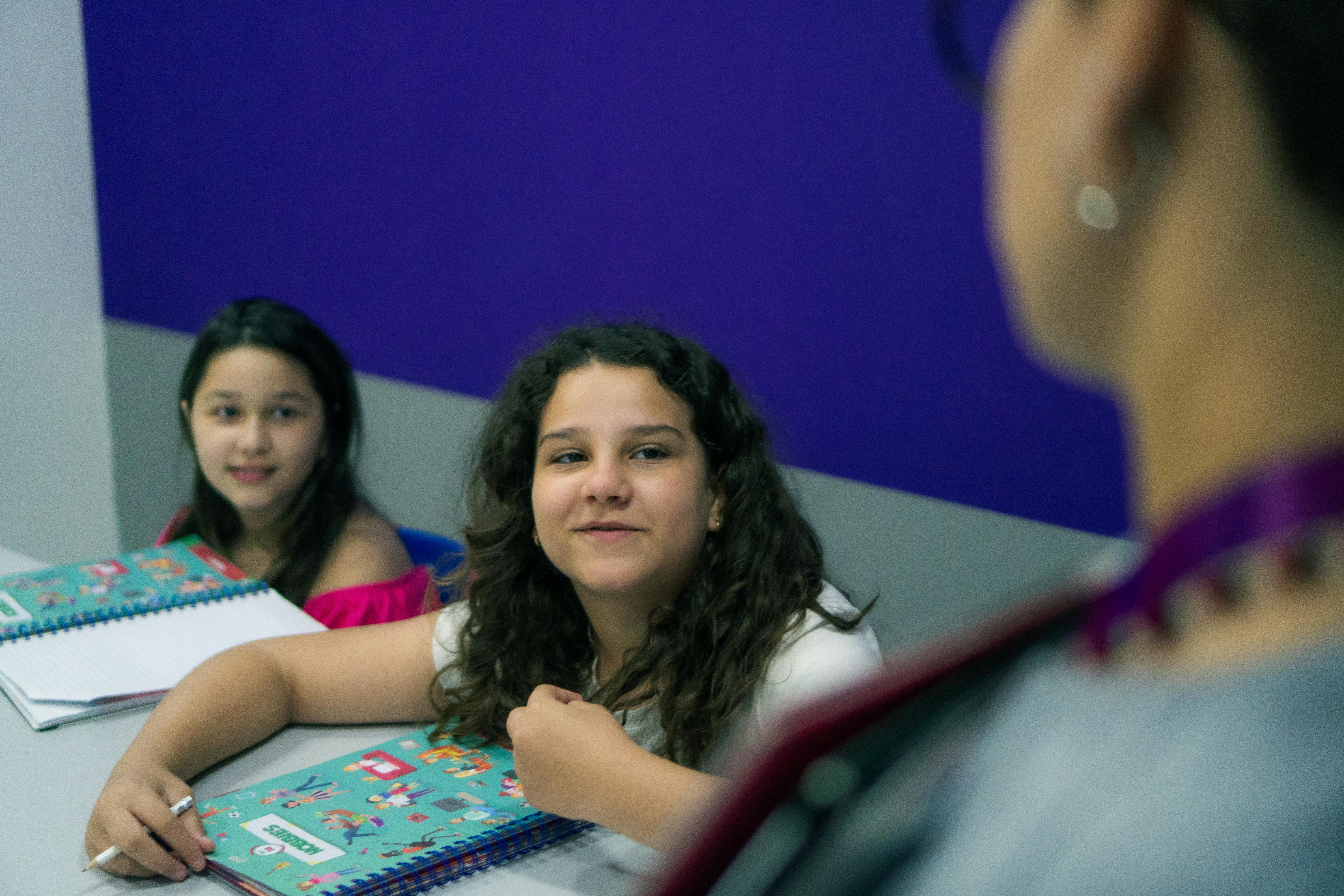 Duas crianças sorrindo e olhando para seus professores. 