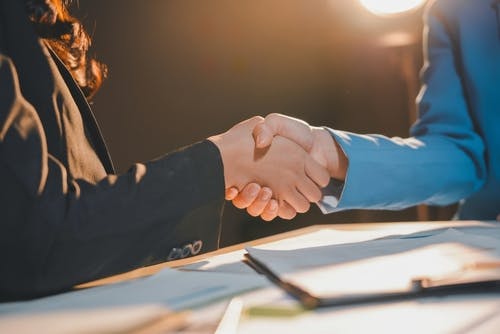 Duas pessoas apertando as mãos, como se estivessem "fechando negócio".