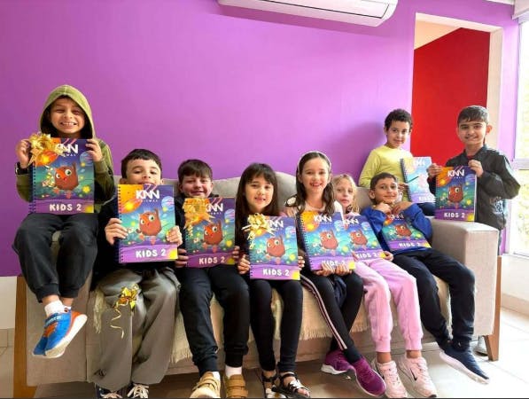 Turma do KNN Kids com os livros em mãos e todos felizes sentados em um sofá.
