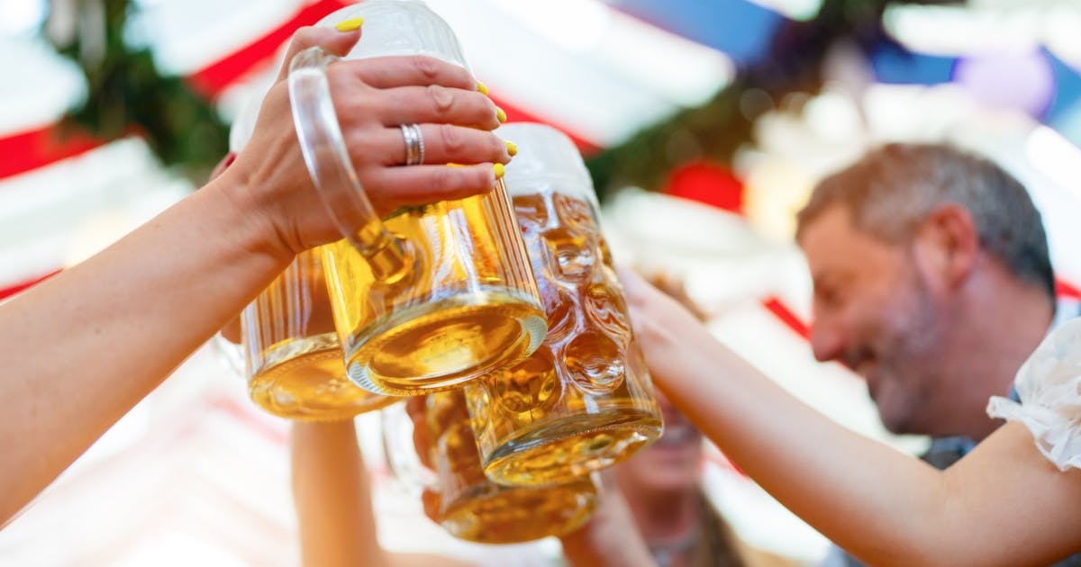 Várias pessoas brindando seus copos de chopp, comemorando a famosa festa "Oktoberfest" na Alemanha, em Munique.