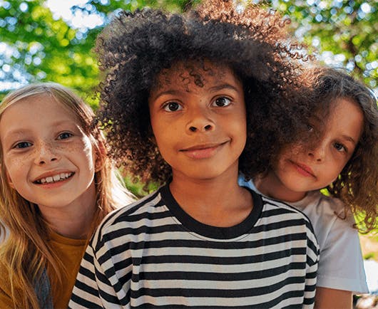 Três crianças lado a lado olhando para a foto com expressão de felicidade.
