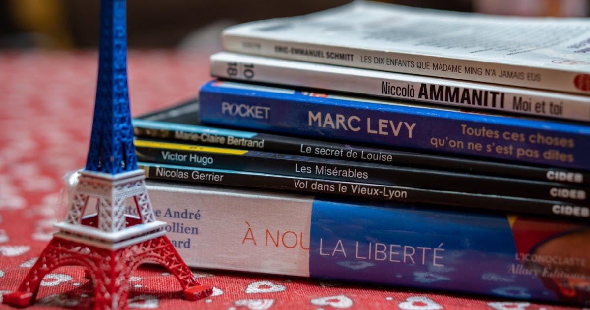 Livros em cima de uma mesa e, ao lado, uma miniatura da torre Eiffel.