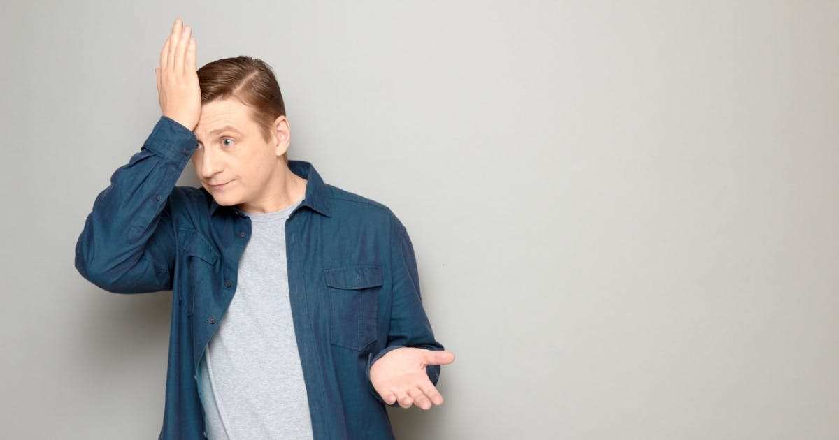 Homem com a mão direita na testa e a outra aberta, com reação de lamento.