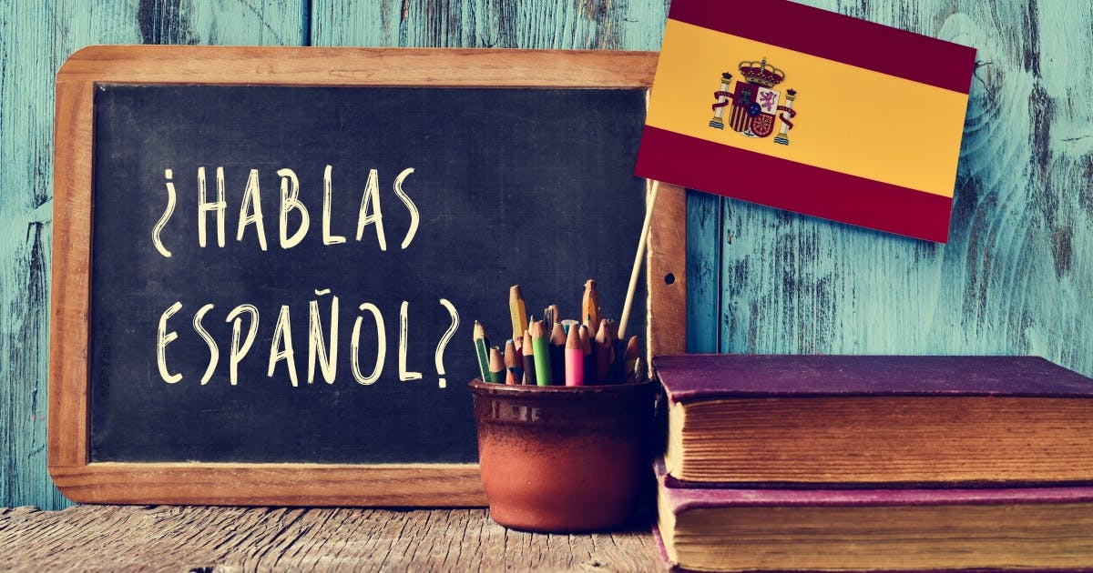 Quadro com a escrita "HABLAS ESPAÑOL?", livros, lápis e uma bandeira da Espanha.
