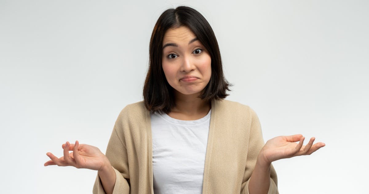 Mulher com expressão de dúvida olhando para a foto e com as duas mãos abertas.