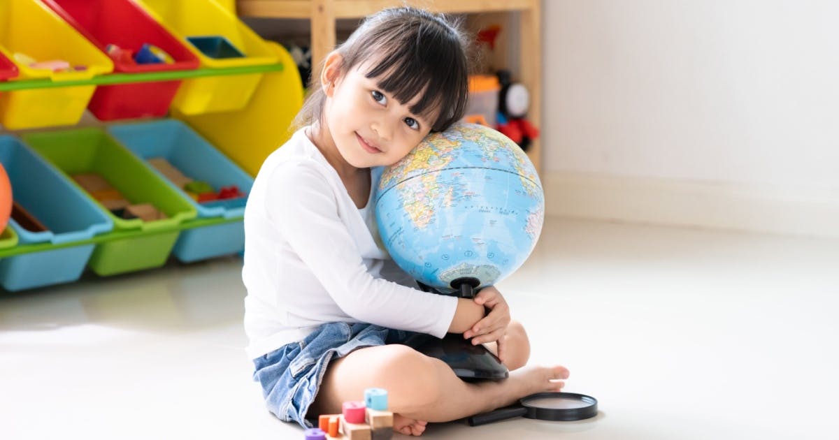 Menina asiática abraçada em um globo de plástico.