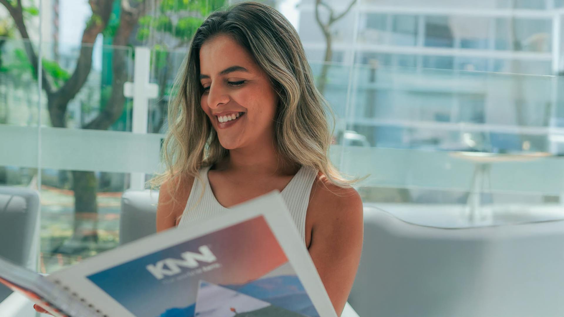 Mulher com o livro da KNN Idiomas aberto e ela está sorrindo.