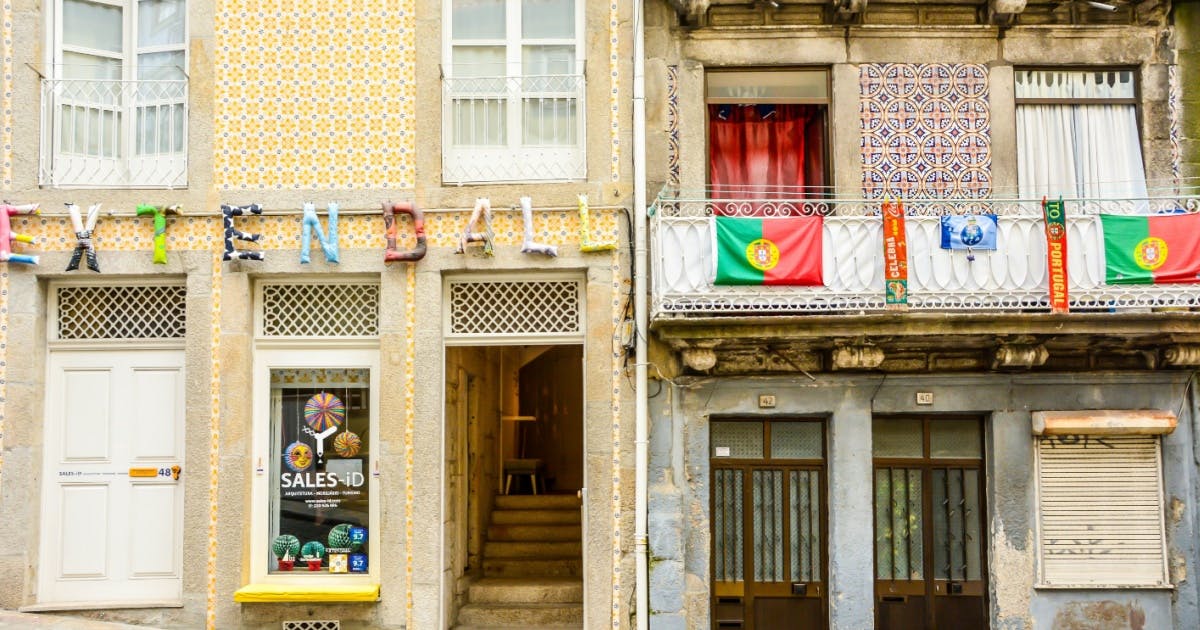 Foto da fachada de duas lojas e uma está com bandeiras de Portugal.