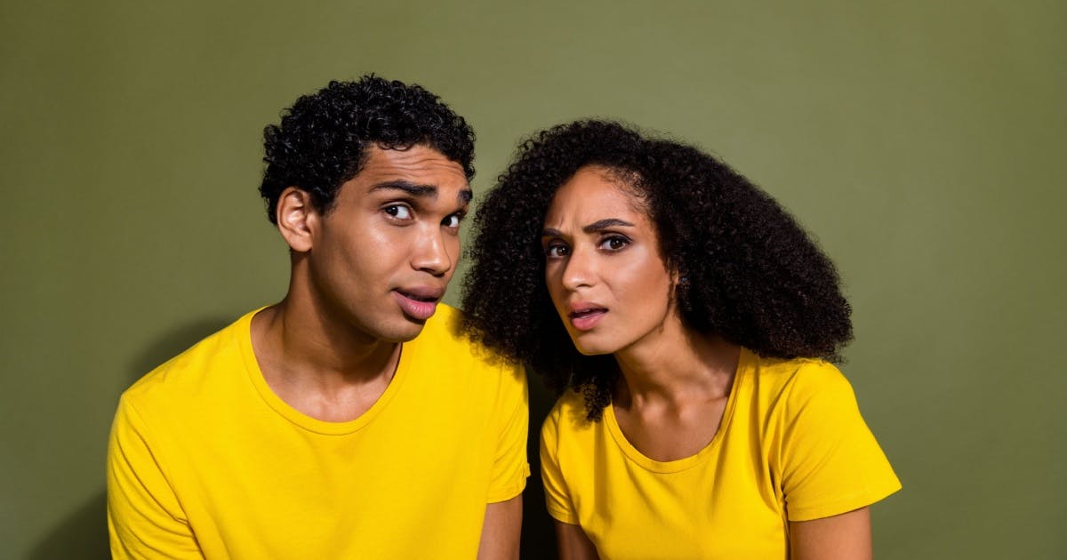 Duas pessoas vestindo camiseta amarela com expressão de dúvida e olhando para a foto.