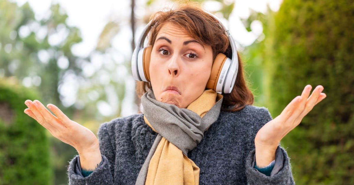 Mulher com roupa de inverno, fones de ouvido e com expressão de dúvida olhando para a foto.