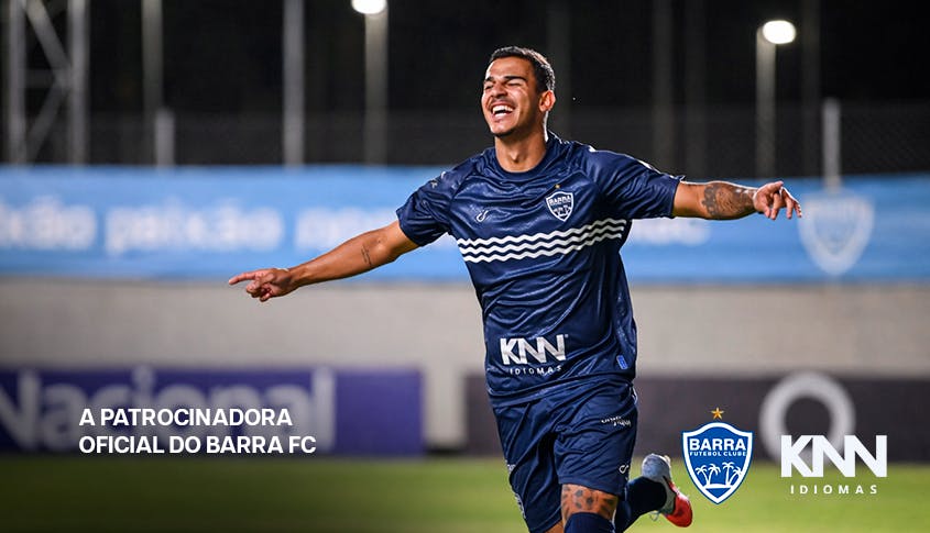 Jogador do Barra Futebol Clube feliz e sorridente comemorando um gol. Na imagem tem as logos da KNN Idiomas e Barra FC.