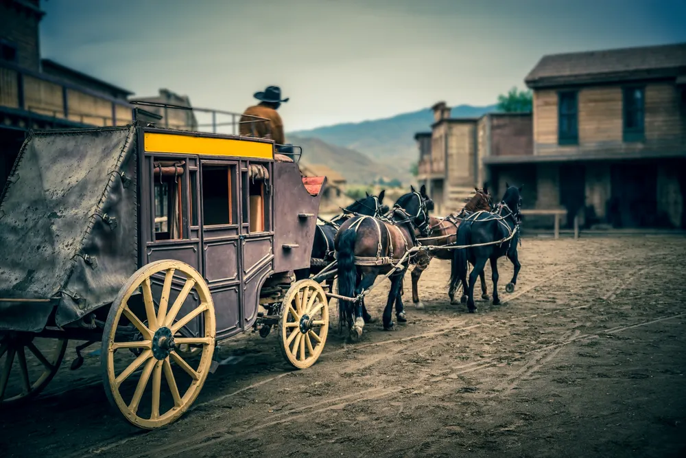 Imagem de um faroeste americano com carroça e cavalos.