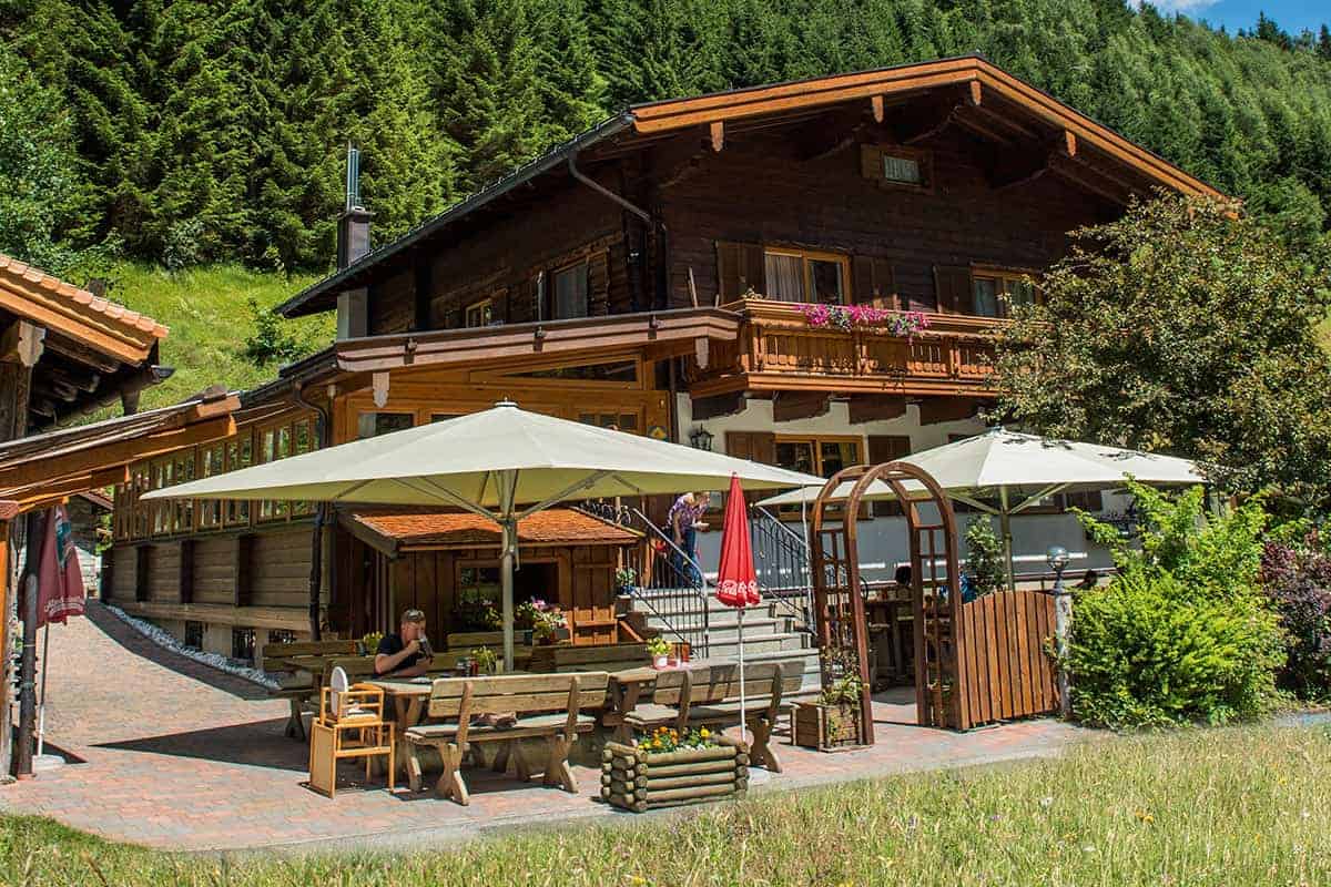 Landgasthaus Weixen in Rauris. Man sieht ein schönes, traditionalles, österreichische Haus am Bild mit Terasse. Finde deine Ferienwohnung bei  we rent apartments