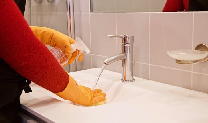 femme de ménage lavant un lavabo avant un état des lieux