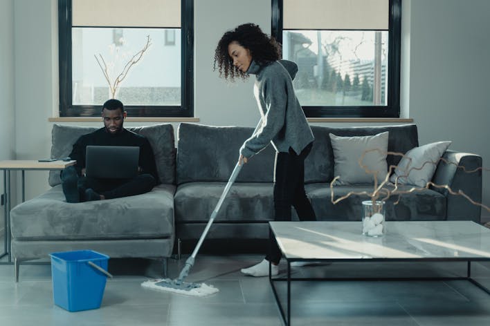Cleaner mopping the floor with a mop and a blue water container- office cleaning services near me 