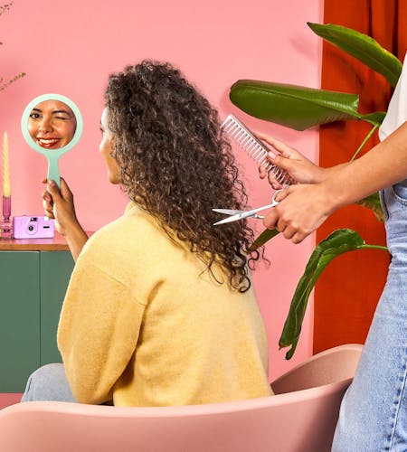 Une coiffeuse à domicile en train de couper les cheveux d'une cliente