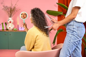 Une coiffeuse à domicile en train de couper les cheveux d'une cliente