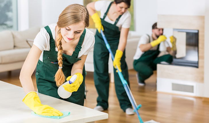 three domestic cleaners doing the cleaning in green uniforms and yellow gloves 
