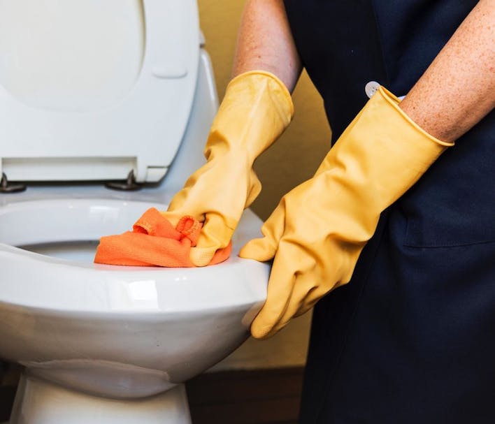 nettoyage des toilettes avec des produits ménagers, des gants et une chiffonnette en microfibre