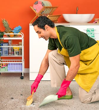 Homme de ménage qui nettoie le sol avec une pelle et une balayette
