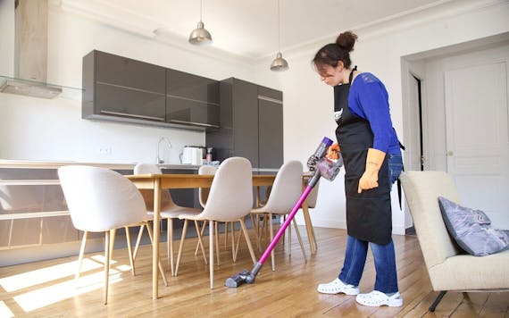 A woman cleaning the floor with a vacuum cleaner.