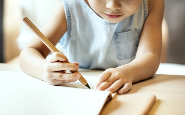 Un enfant en crèche dessine sur un cahier