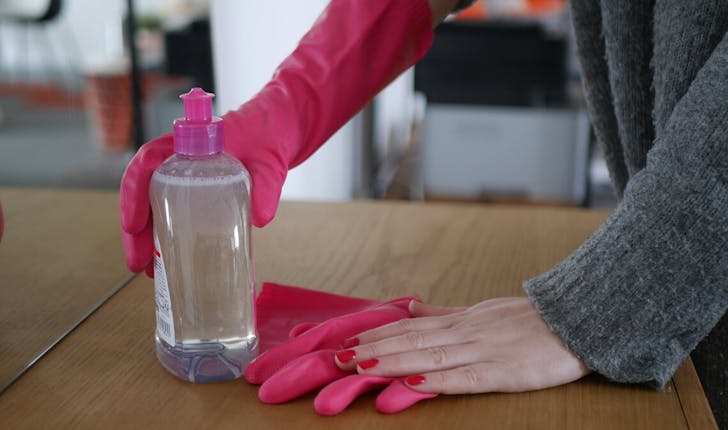 Laver une table en bois avec des produits de ménage et des gants