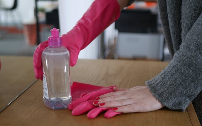 Laver une table en bois avec des produits de ménage et des gants