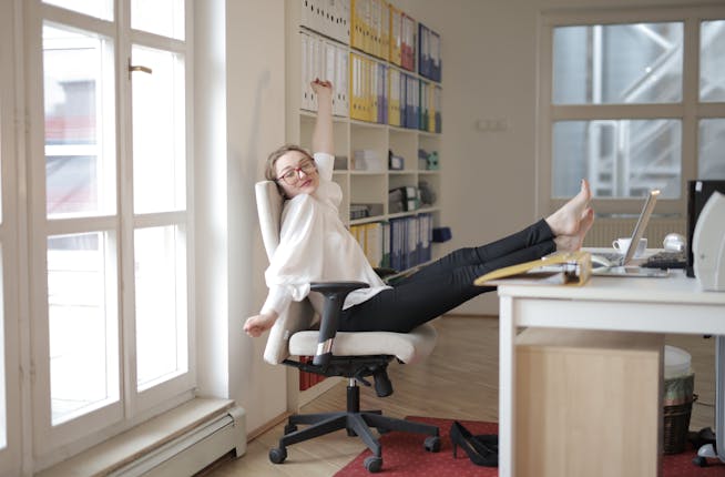 happy woman employee relaxing with feet on table in a office