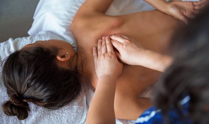 Une masseuse à domicile fait un massage palper-rouler à une femme.