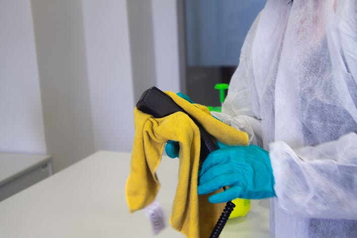 cleaner wiping a phone with a yellow cloth
