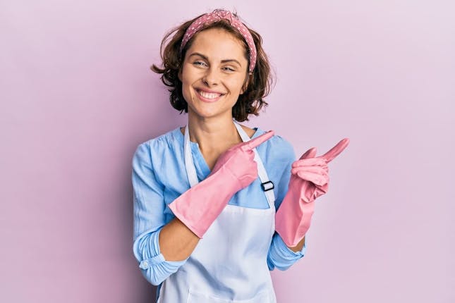 Happy part-time cleaner waring pink cleaning gloves