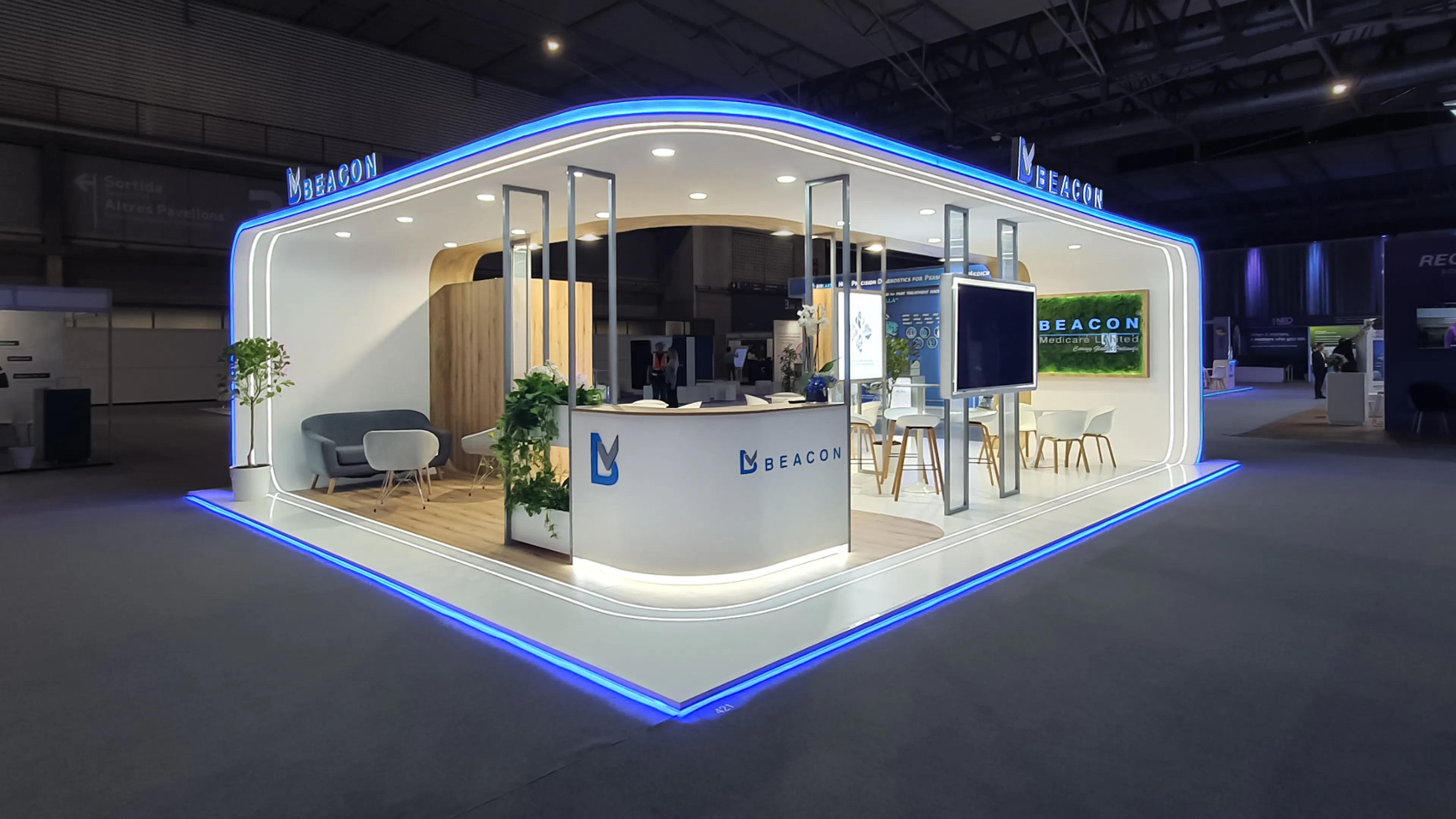 Beacon Medicare exhibition stand with white and wood finishes, blue LED trim, lounge seating, and reception counter