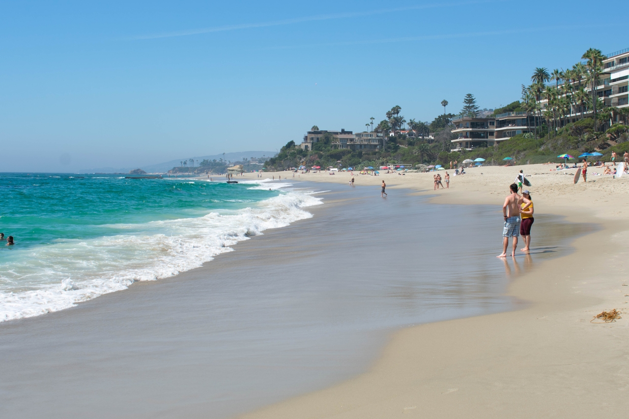 Beach goers on the sand by the water at Coast Royale Beach in Orange County 