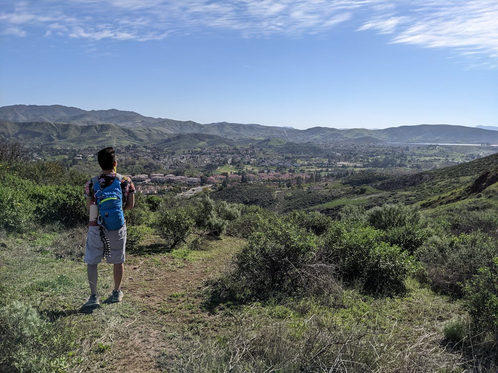 Hiker taking in the wide open mountain and valley scenery from Mount McCoy in Simi Valley Ventura County 
