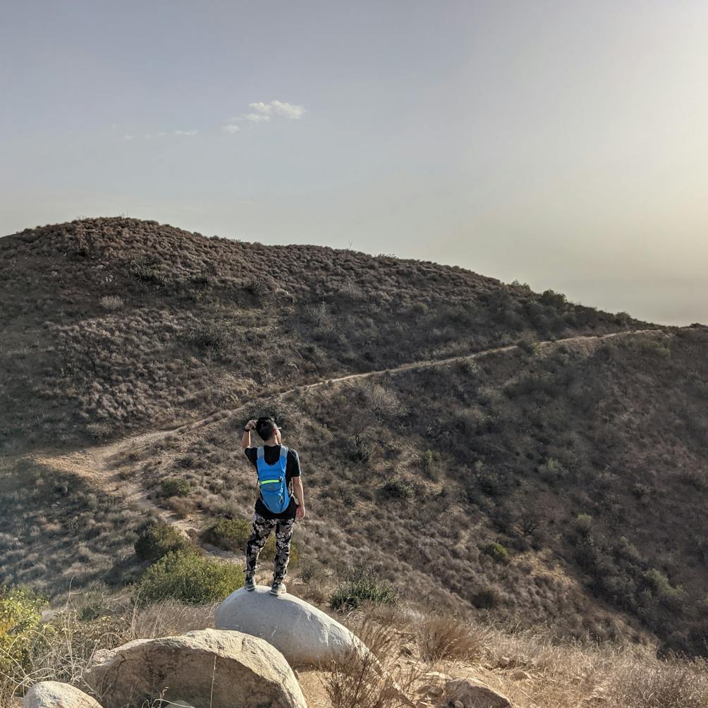 Hiker on a rock taking pictures of the sun shadows at Shadow Hills near Burbank