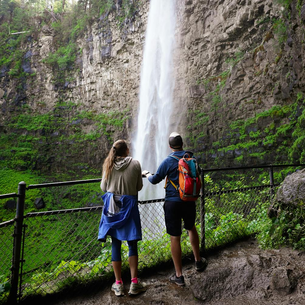Two people at the overlook and watching Watson Falls in Southern Oregon 