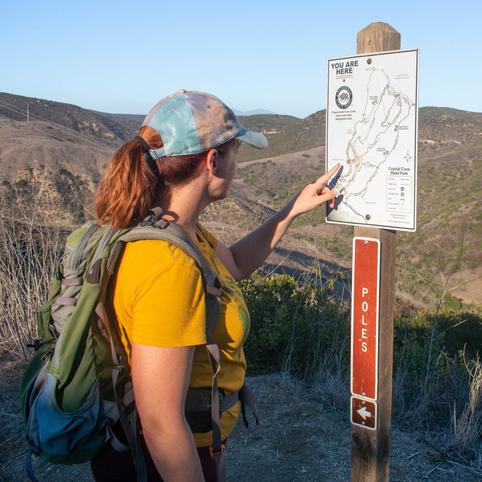 Hiker looking at map post at Crystal Cove State Park in Orange County 