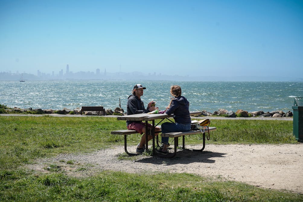 Two people enjoying a picnic overlooking the San Francisco Bay at Cesar Chavez Regional Park in Berkeley 