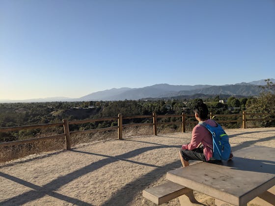 Hiker sitting at a picnic table overlooking the mountains at The Antonovich Trail in San Dimas